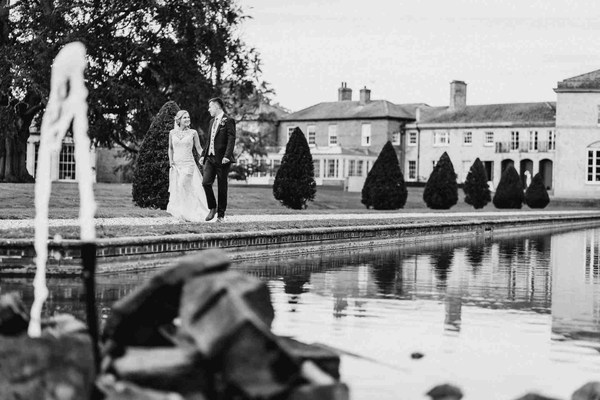 STUBTON HALL | Amelia & Tom 16 Bride and groom walk alongside lake at Stubton Hall wedding venue