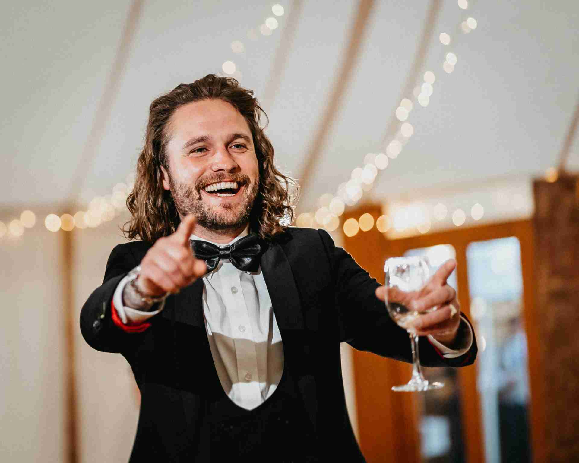 HOME 31 a man in a tuxedo pointing at a wine glass