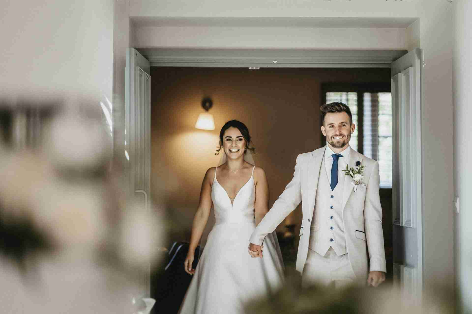 VENUE GUIDE | Doddington Hall 54 a man and woman in a white suit and white dress walking down a hallway